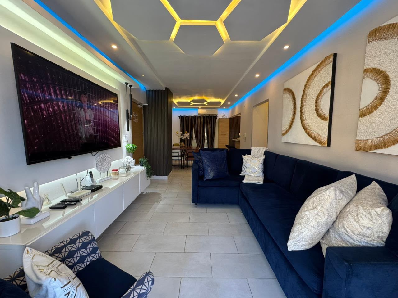 Un salon moderne avec un téléviseur à écran plat, un canapé bleu foncé et un meuble de rangement blanc.