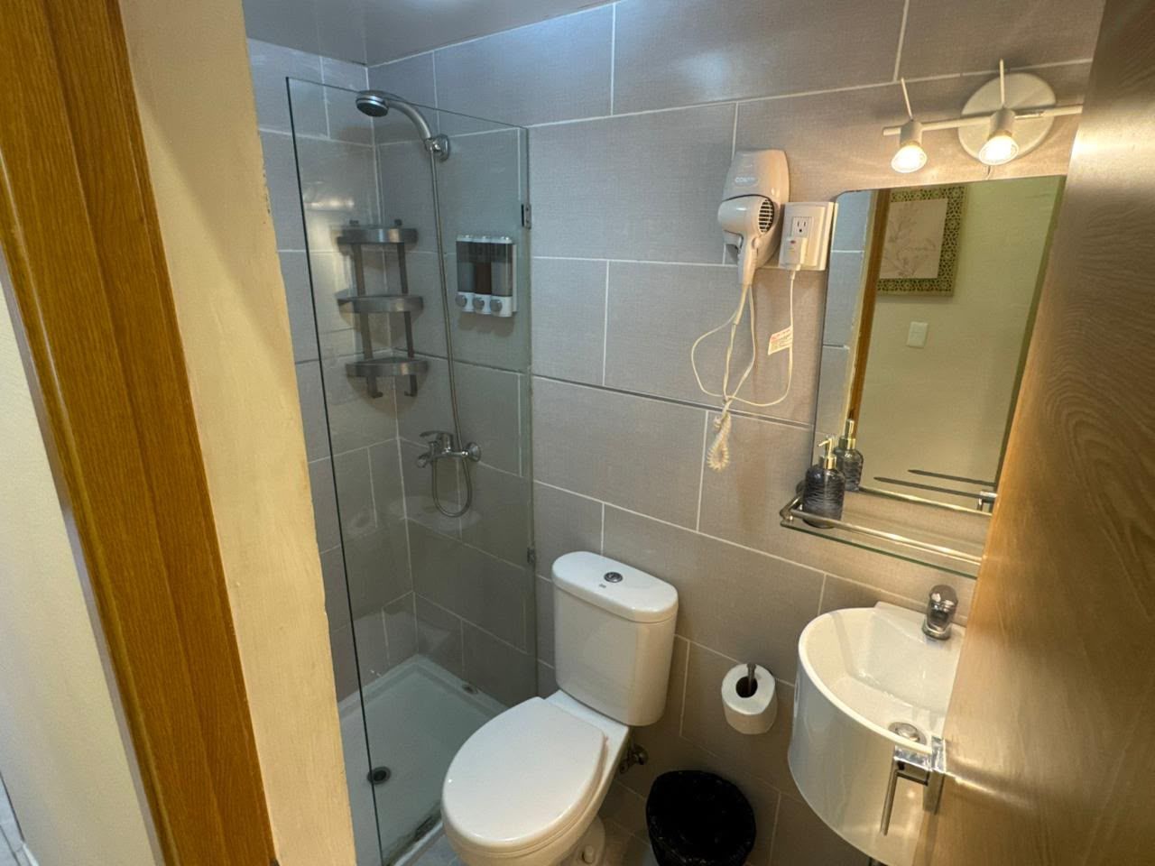 Une salle de bain avec une douche à parois de verre, des toilettes, un lavabo et un miroir.