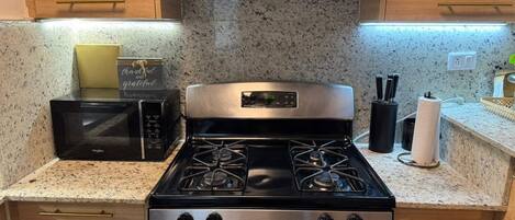 Una cocina con microondas, estufa y armarios de madera.