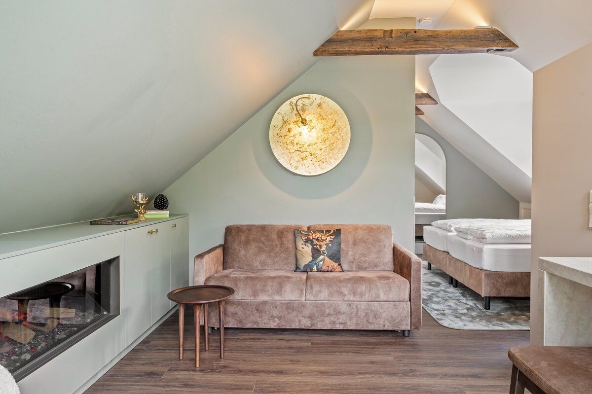 Ein Schlafzimmer im Loft-Stil mit schrägem Dach, Kamin, einer Couch und einem Bett.