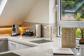 A modern kitchen with a built-in sink, a coffee machine, and a welcome sign.