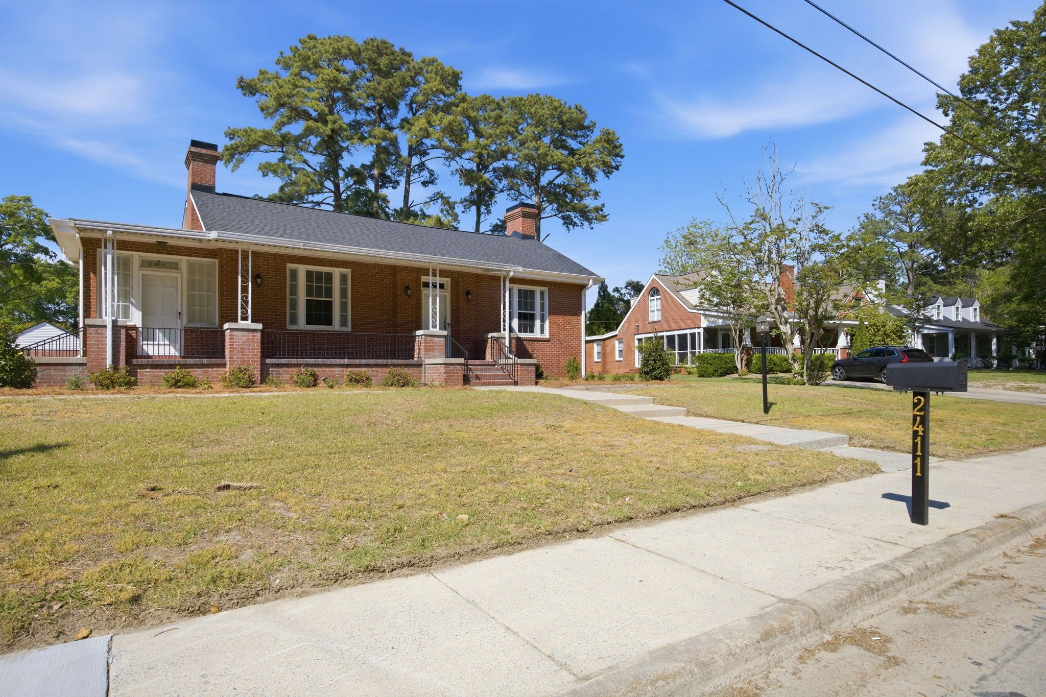 A two-story brick house with a front porch, a mailbox, and a well-maintained lawn.