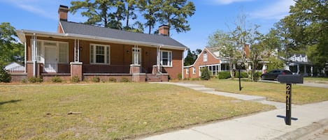 A two-story brick house with a front porch, a mailbox, and a well-maintained lawn.