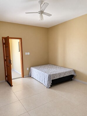 A bedroom with a bed, a ceiling fan, a door, and a light switch.