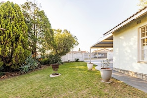 A well-maintained garden with a variety of plants and a small decorative structure. - Cozy Bachelor Apartment, Best Value for Money (Alberton)