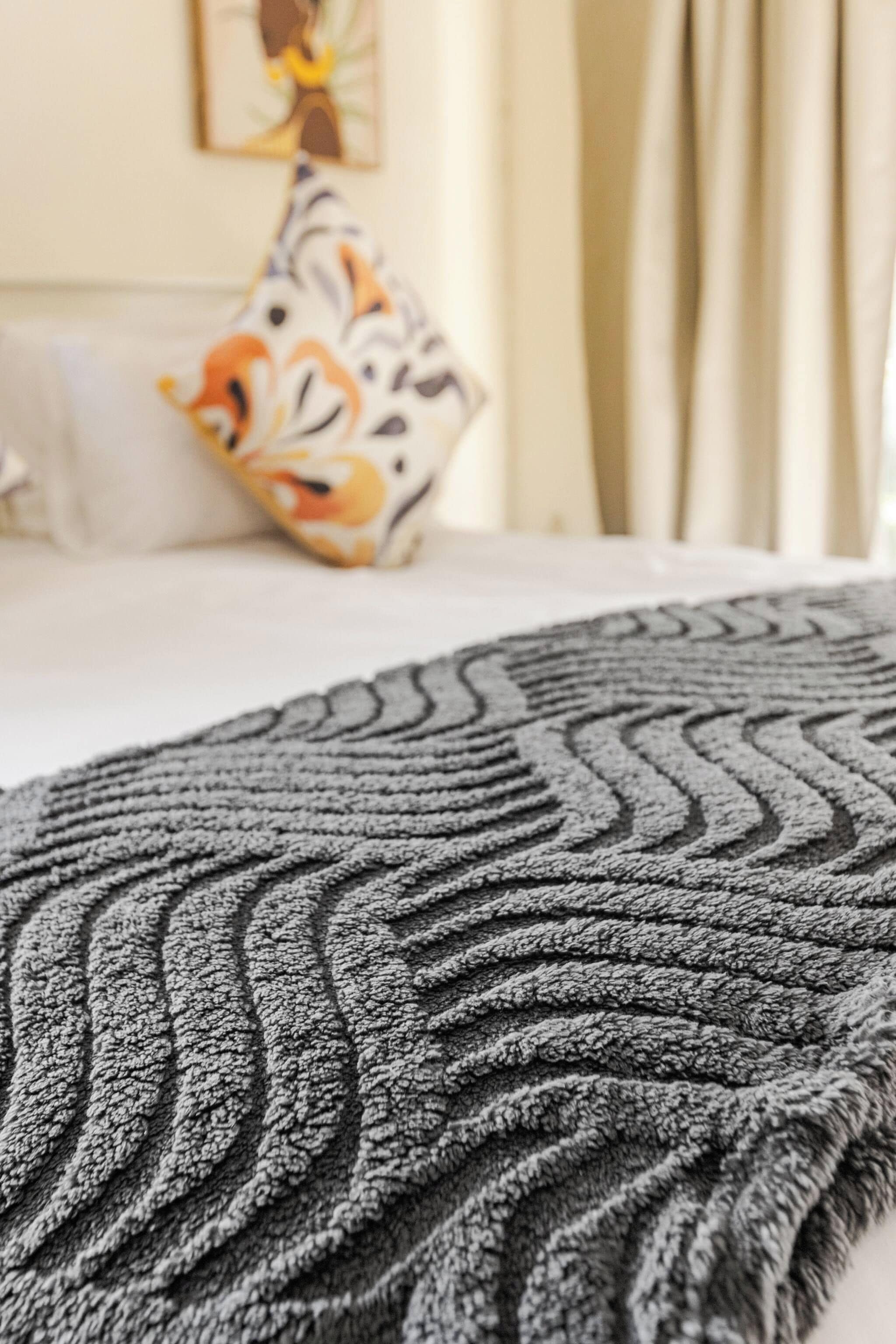 Een detailopname van een bed met een deken met een zigzagpatroon.