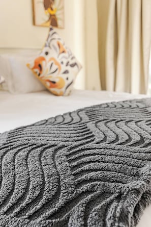 Un gros plan d’une couverture à motifs texturés, avec un motif en zigzag, posée sur un lit.
