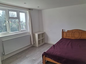 A bedroom with a bed, a window, a radiator, and a shelf. - House Sleeps 5 With Wifi (Ilford)