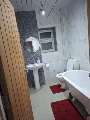 Une salle de bain avec un lavabo blanc, des toilettes et une baignoire.
