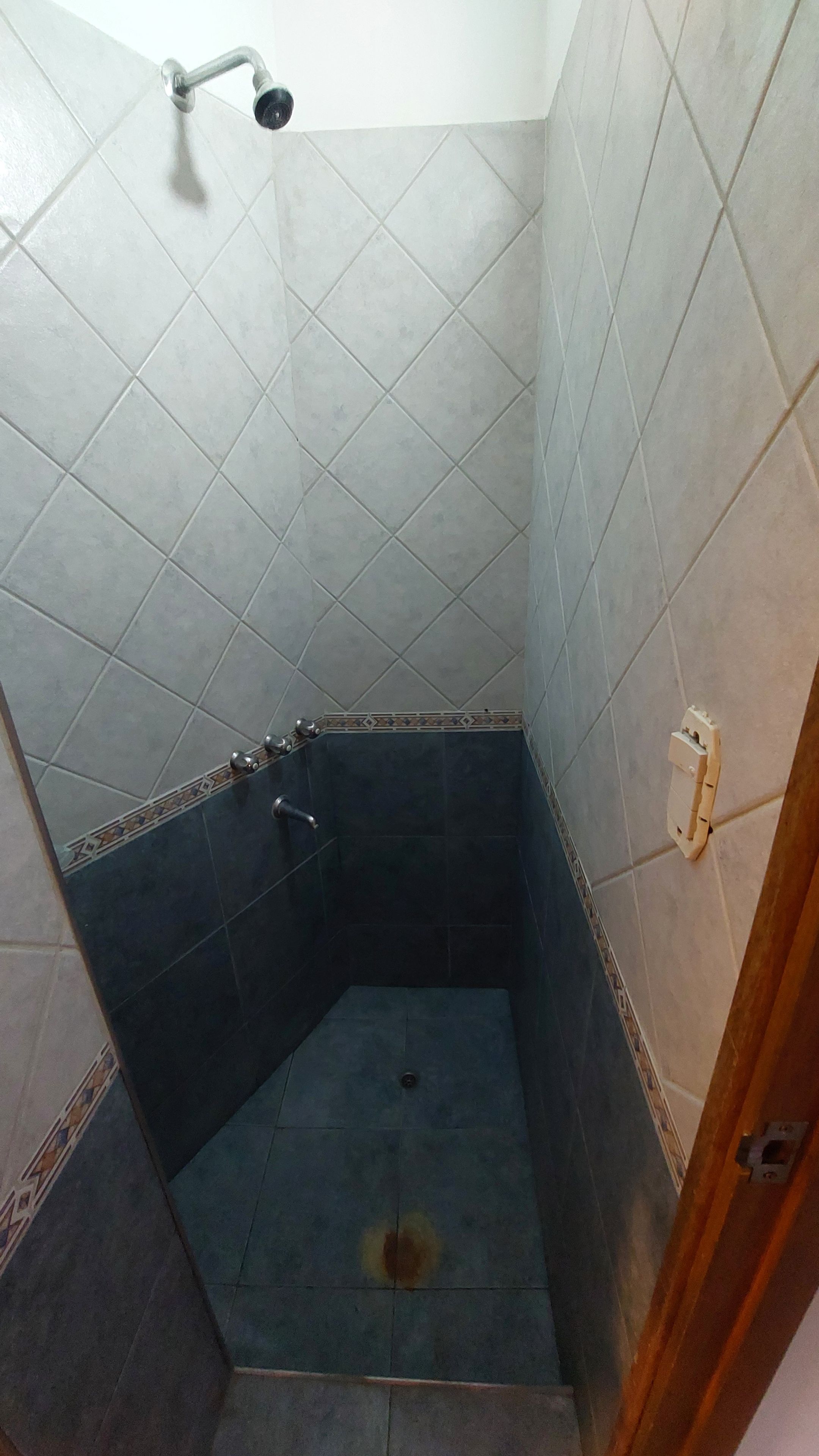 A small, enclosed shower area with tiled walls and a showerhead.