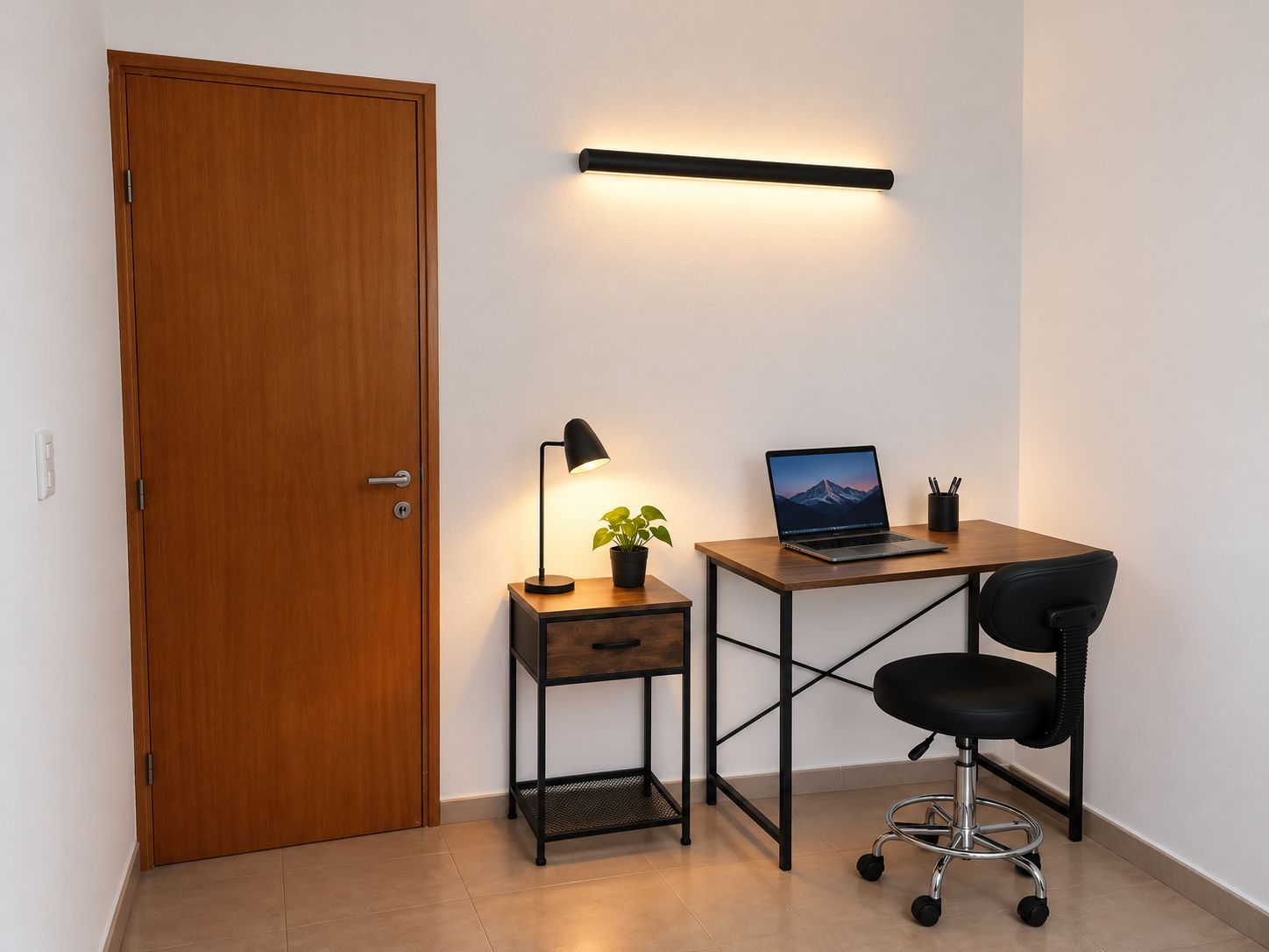 A small office space with a wooden desk, a laptop, a desk lamp, a potted plant, and a black office chair.