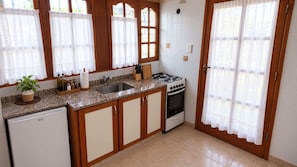 Una cocina con armarios de madera, un lavamanos, una estufa y un refrigerador.