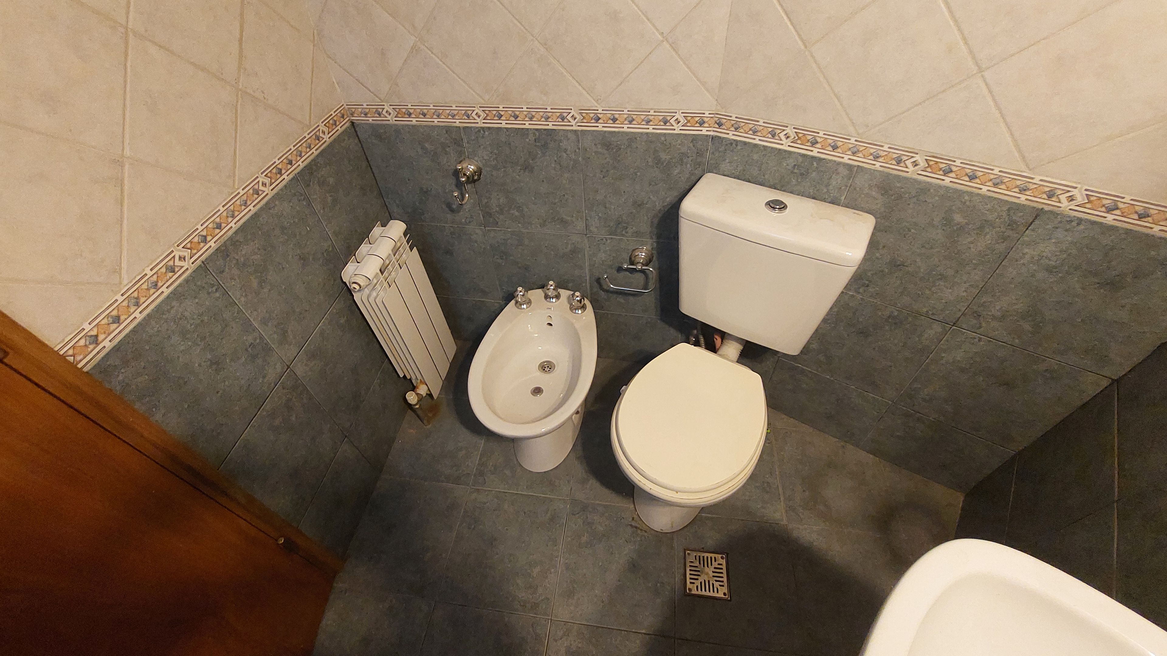 Ein Badezimmer mit integriertem Bidet, Toilette und Heizkörper.
