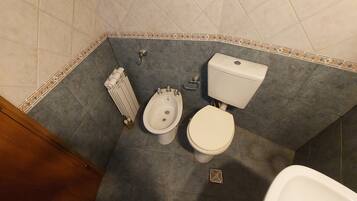 Ein Badezimmer mit integriertem Bidet, Toilette und Heizkörper.