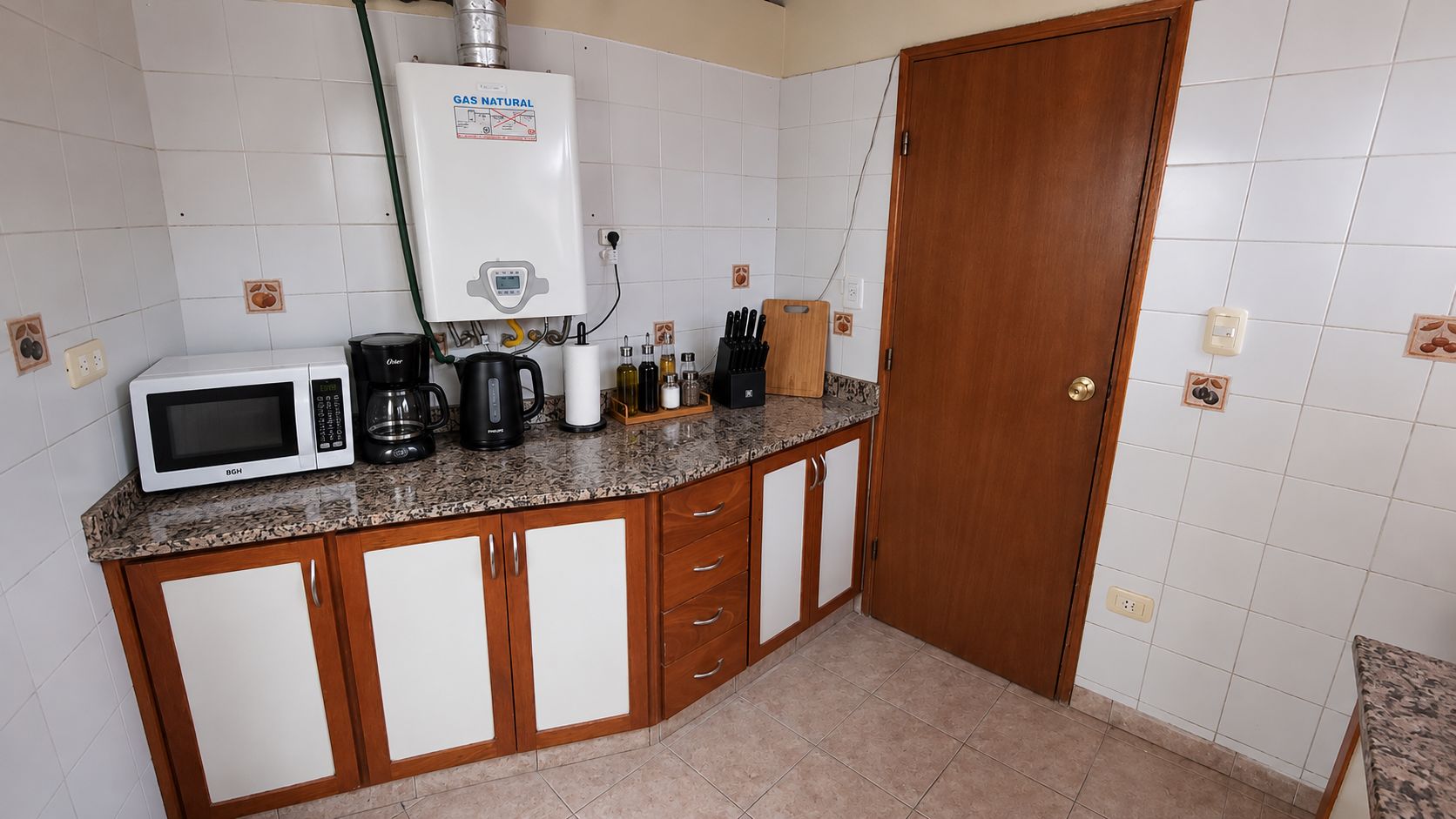 A kitchen with a microwave, coffee maker, and a water heater on the countertop.