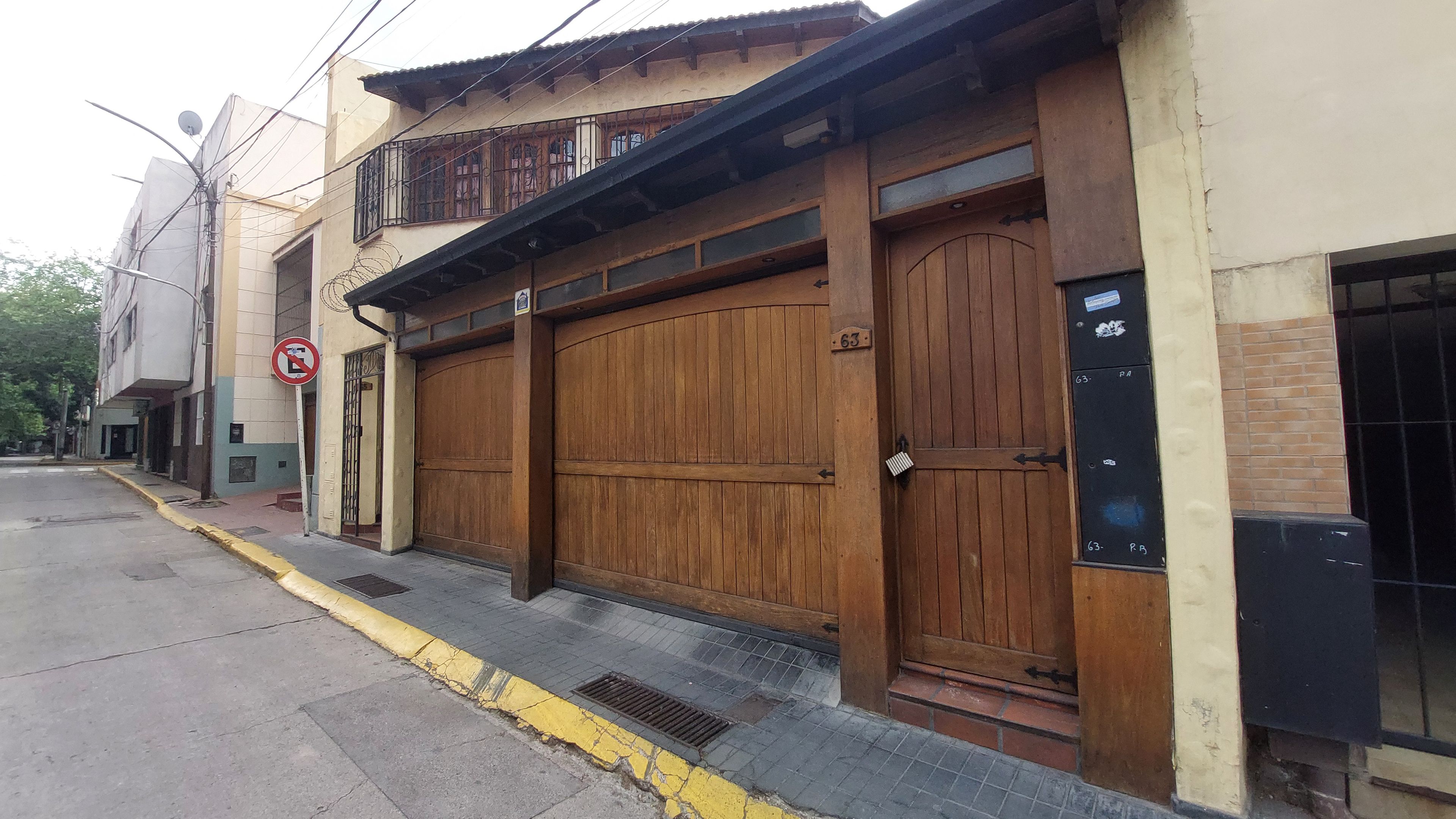 A building with a large wooden garage door, a no parking sign, and a mailbox.