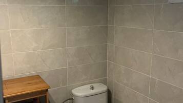 A small bathroom with a white sink, toilet, and a wooden stool.
