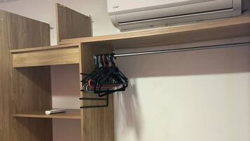 Una habitación con un armario de madera, una pared blanca y un equipo de aire acondicionado instalado en el techo.