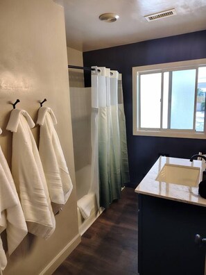 Un baño con ducha, ventana y lavabo.