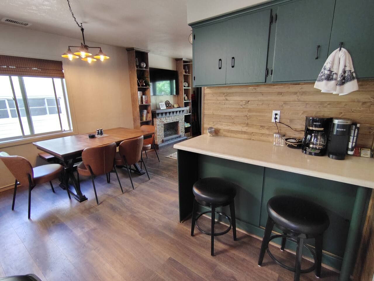 Een moderne keuken met een houten kookeiland, barkrukken en een eethoek met stoelen.
