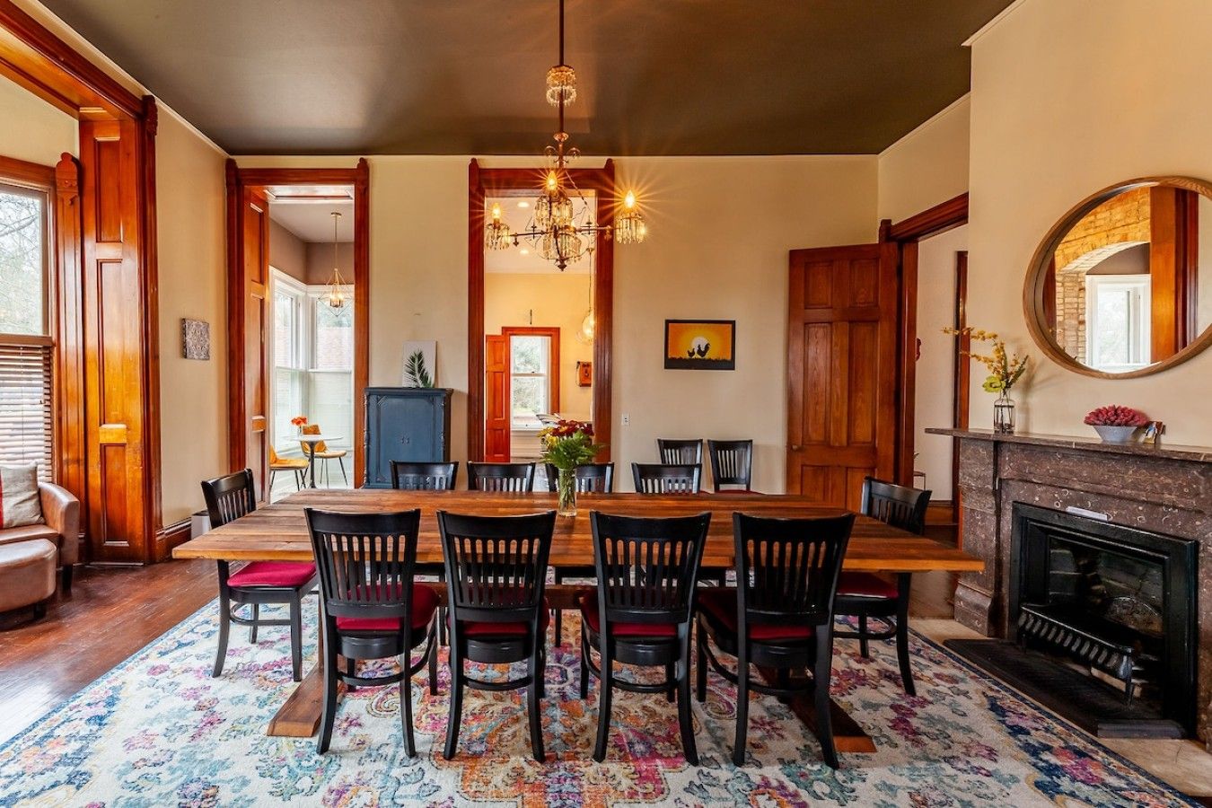 Een eetkamer met een houten tafel en stoelen, een kroonluchter en een open haard.