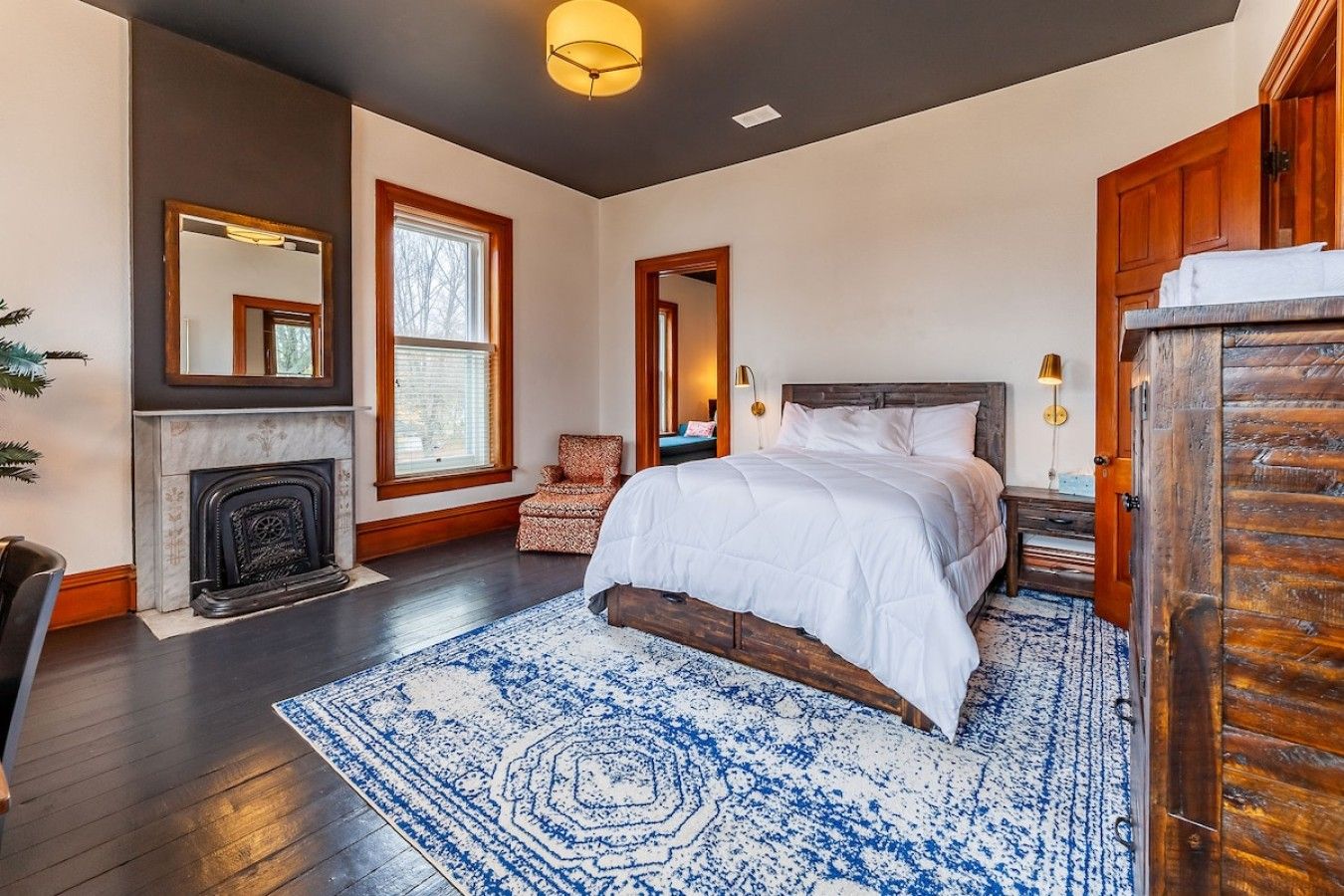 Une chambre à coucher avec un grand lit, une cheminée, un fauteuil et une armoire.