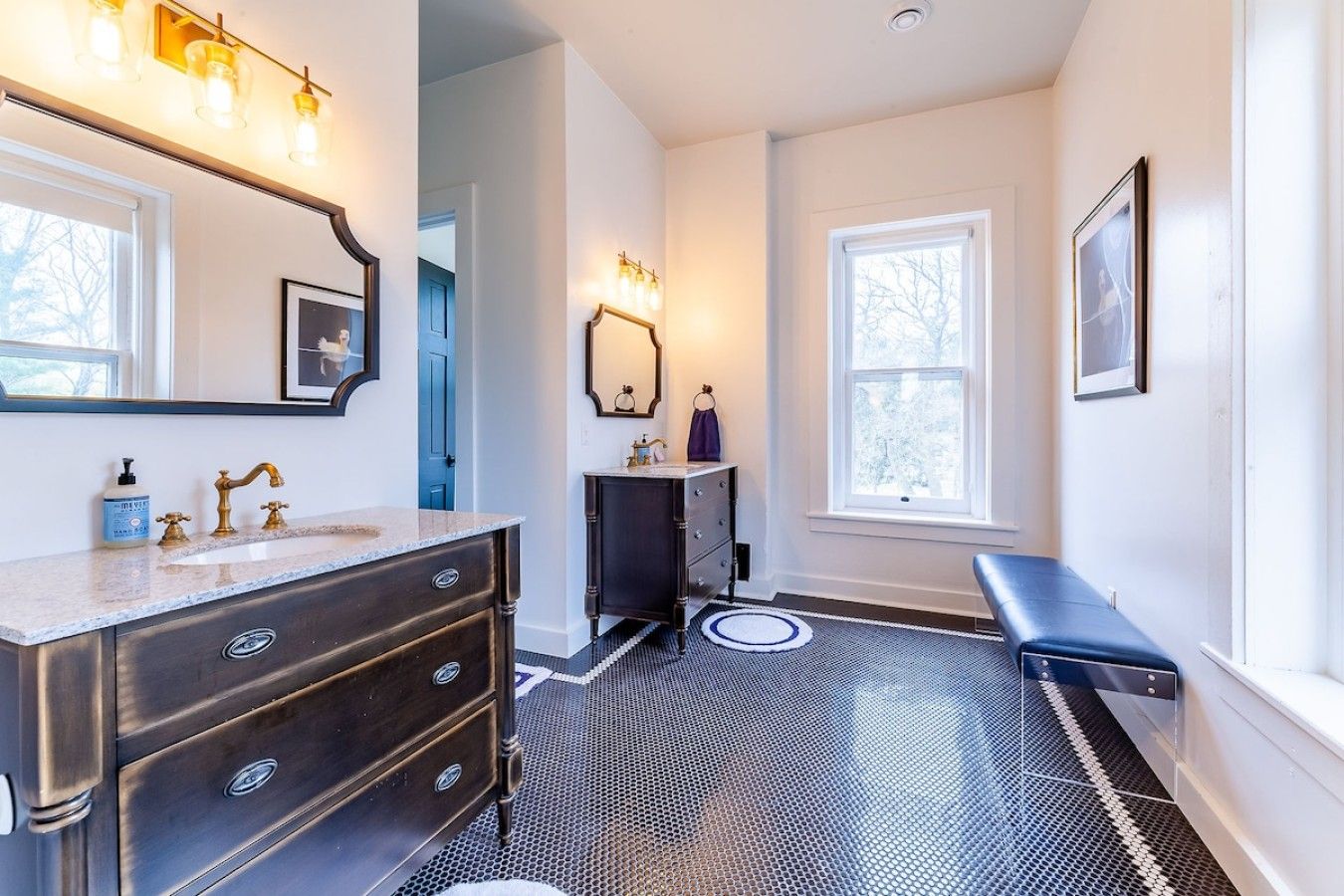 A bathroom with a vanity, a mirror, a sink, and a bench.