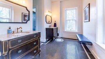 A bathroom with a vanity, a mirror, a sink, and a bench.