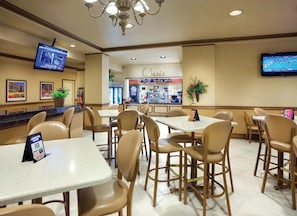 Un restaurante con mesas, sillas, una barra y un televisor en la pared.