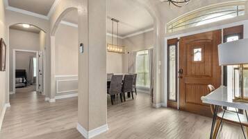 Un interior espacioso con comedor, una puerta de madera y una lámpara moderna.