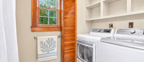 Une buanderie avec une porte en bois, une fenêtre et un lave-linge blanc.