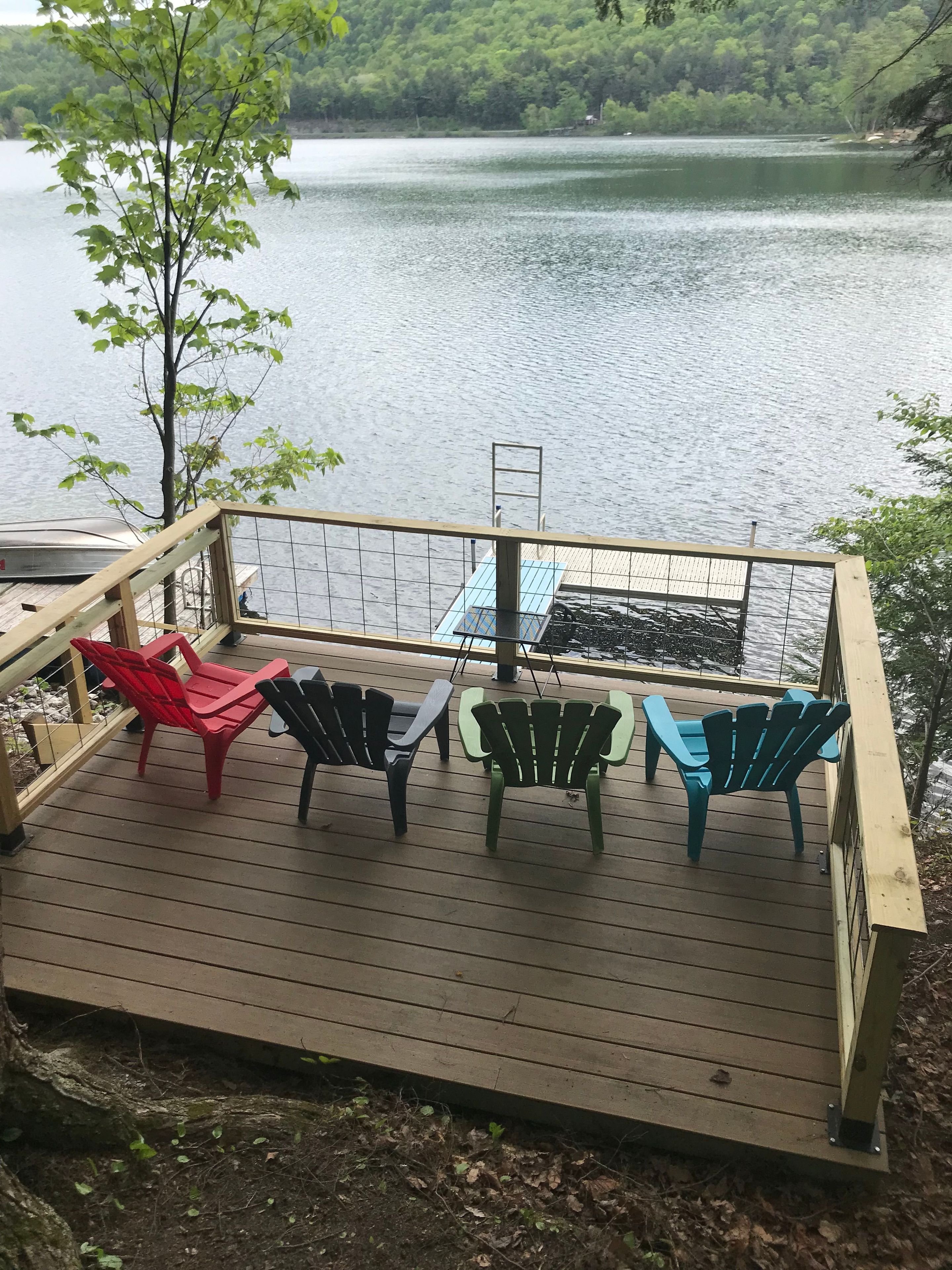 A deck with chairs and a table overlooking a lake.