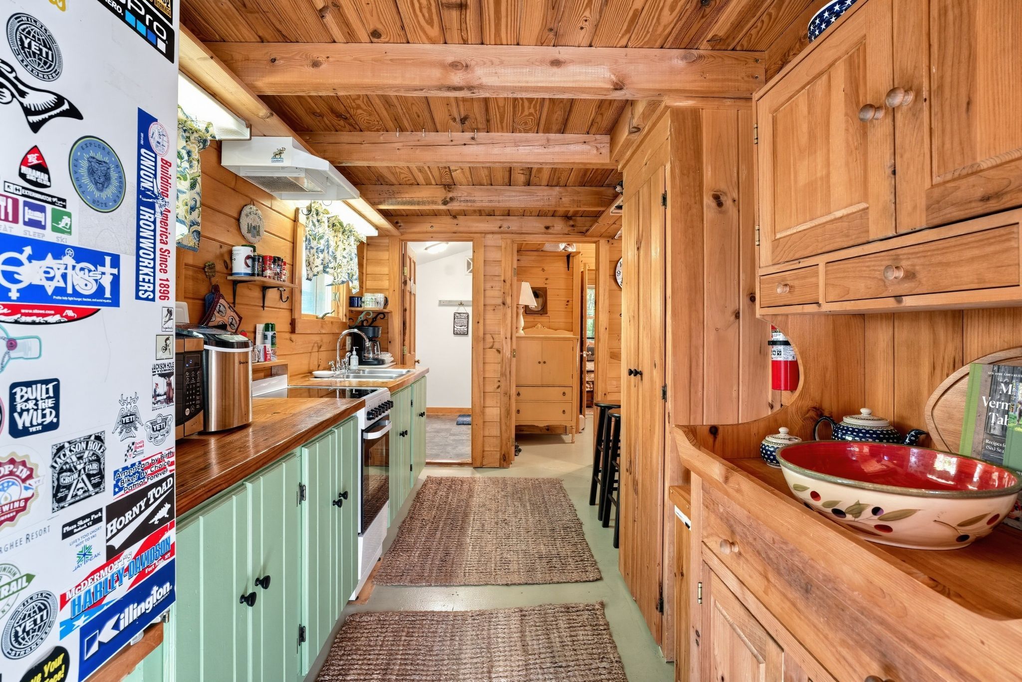 A narrow kitchen with wooden cabinets, a sink, and a stove.