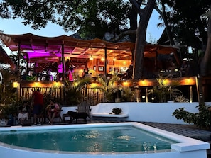 Un área de piscina al aire libre con una zona de estar cubierta y un bar.