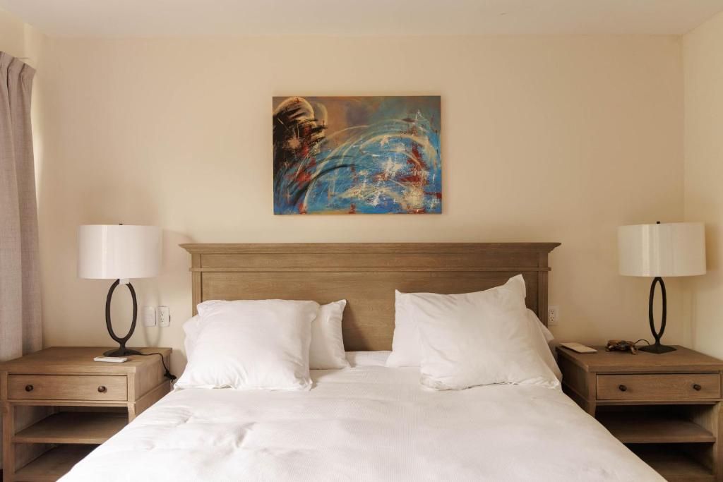 Ein Hotelzimmer mit einem großen Bett, zwei Nachttischen und einem Bild an der Wand.