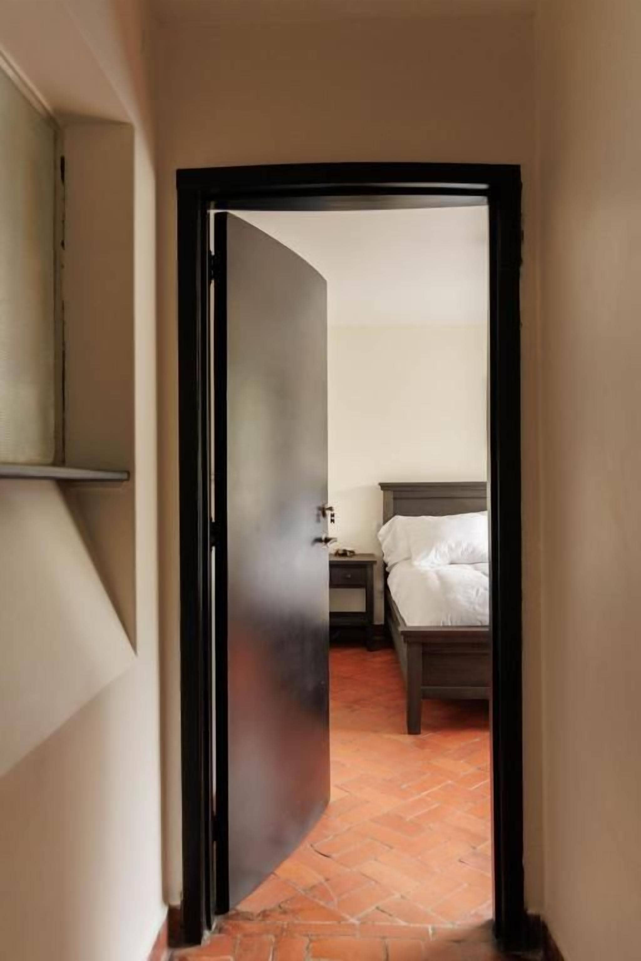 Un couloir étroit mène à une chambre à coucher qui contient un lit et une table de chevet.