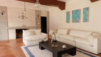 A living room with a fireplace, white sofas, a coffee table, and artwork on the wall.