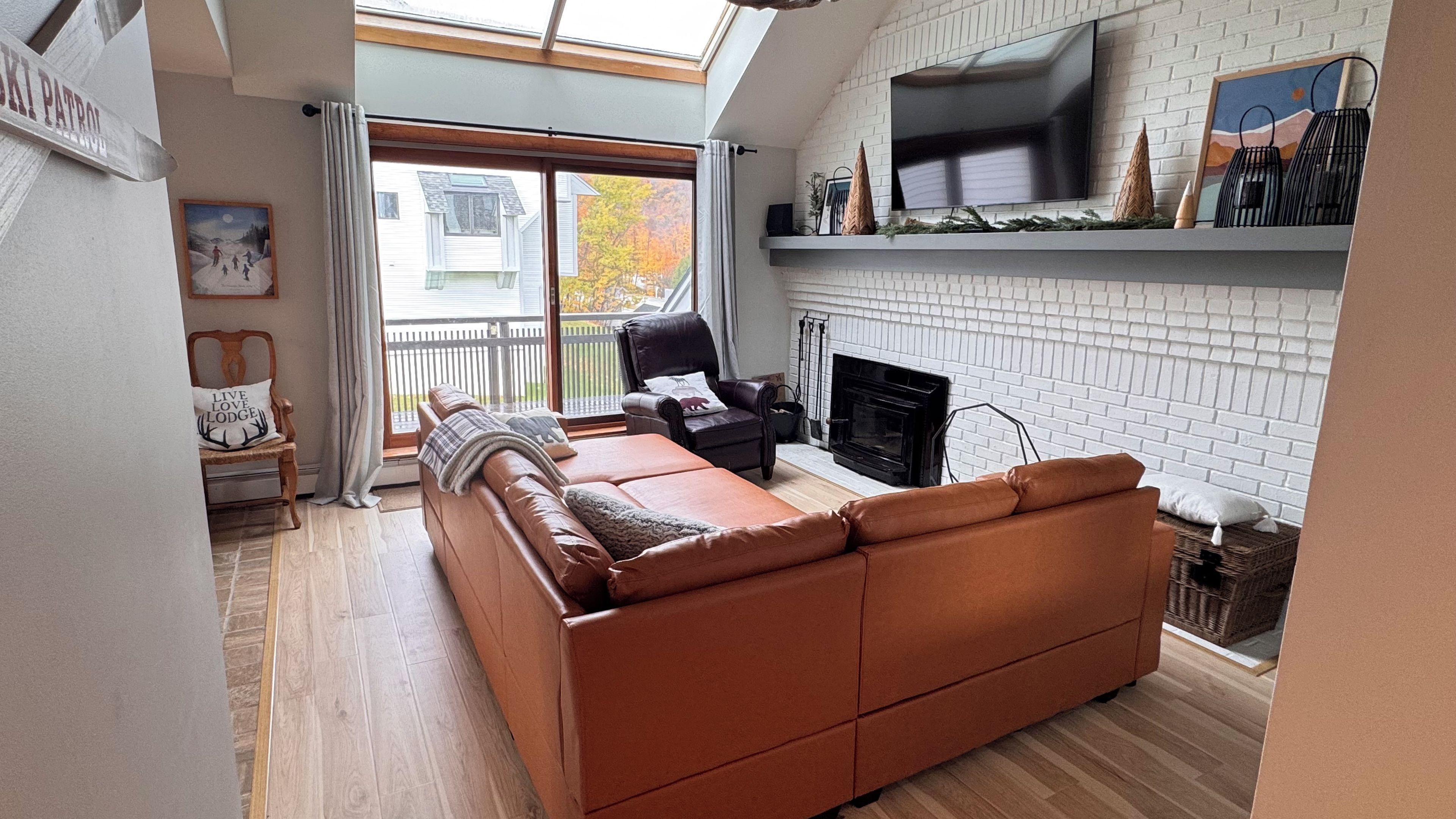Een moderne woonkamer met een bank, een open haard en een televisie die aan een bakstenen muur is bevestigd.