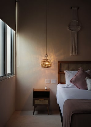 A bedroom with a bed, bedside table, wall-mounted light fixture, and a wall hanging. - Casa Sofía Centro (Merida)