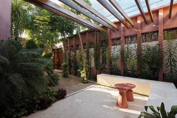 En gårdsplads med pergola, plantekasser og et siddeområde.