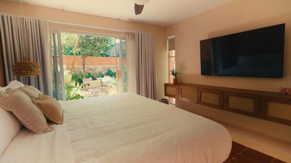 A bedroom with a large bed, a television mounted on the wall, and a view of the outdoors through the window. - Casa Sofía Centro (Merida)