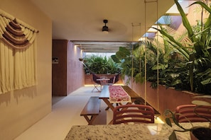 Um espaço interno aconchegante com uma rede, uma mesa de jantar e cadeiras.