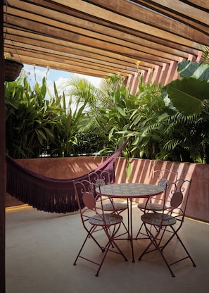 A covered outdoor seating area with a table and chairs, surrounded by lush tropical plants. - Casa Sofía Centro (Merida)