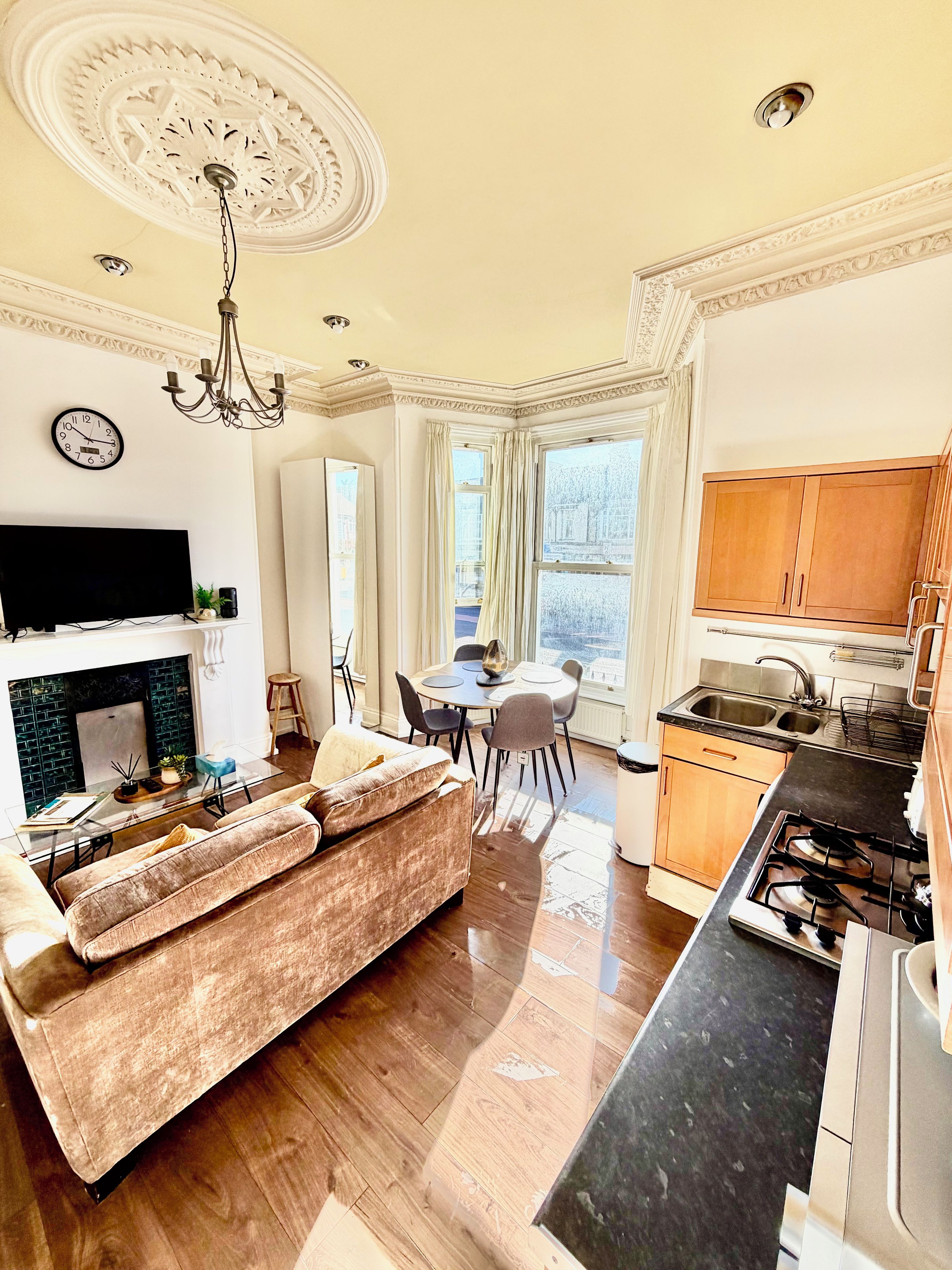 A modern kitchen with a gas stove, wooden cabinets, and a dining area with a round table and chairs.