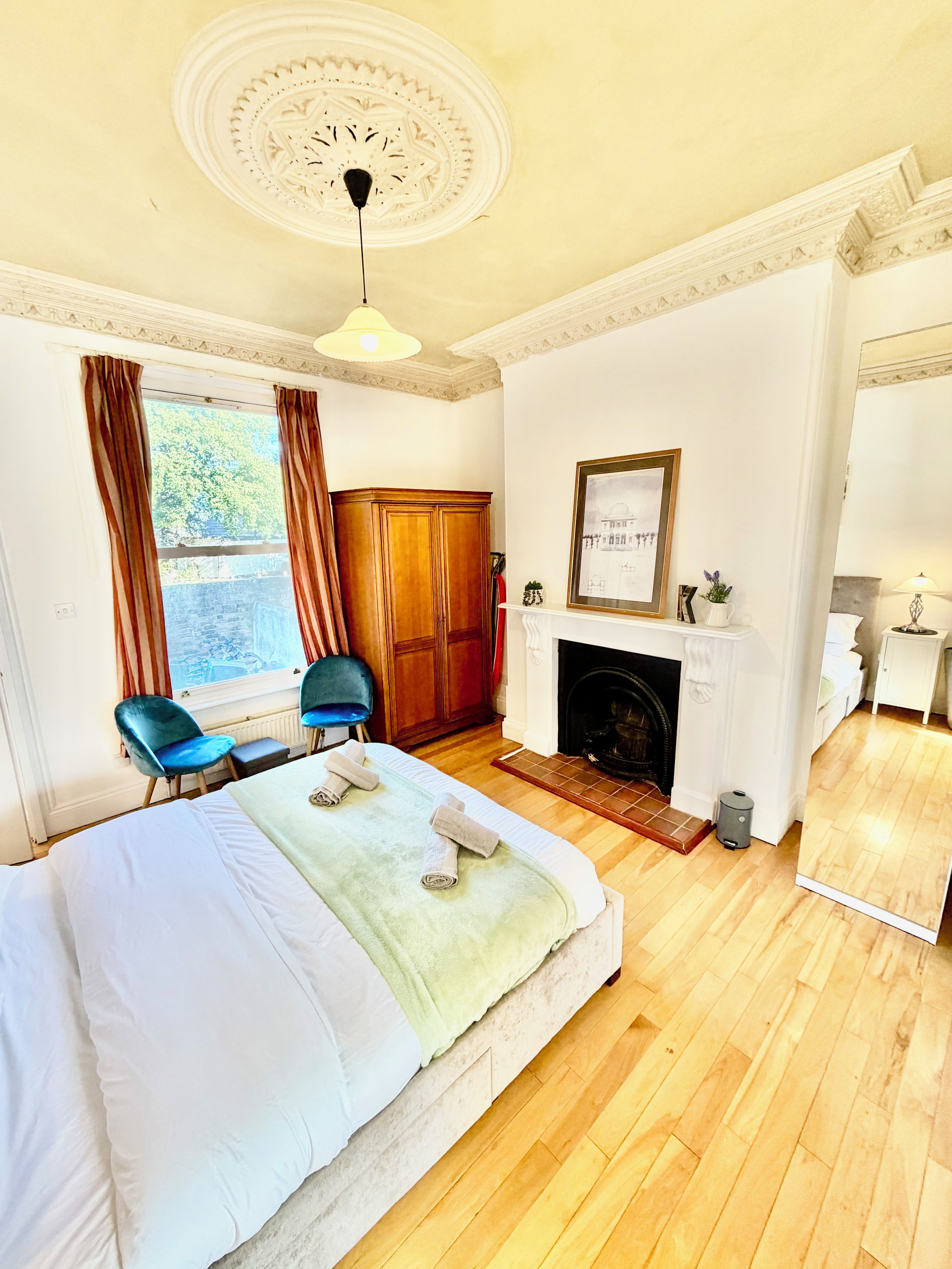 Una habitación de hotel con cama, chimenea, armario, silla y vistas al exterior.