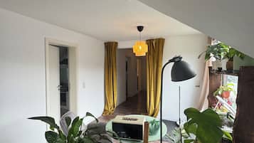 A modern living room with a stone fireplace, a dining table, and a variety of potted plants.