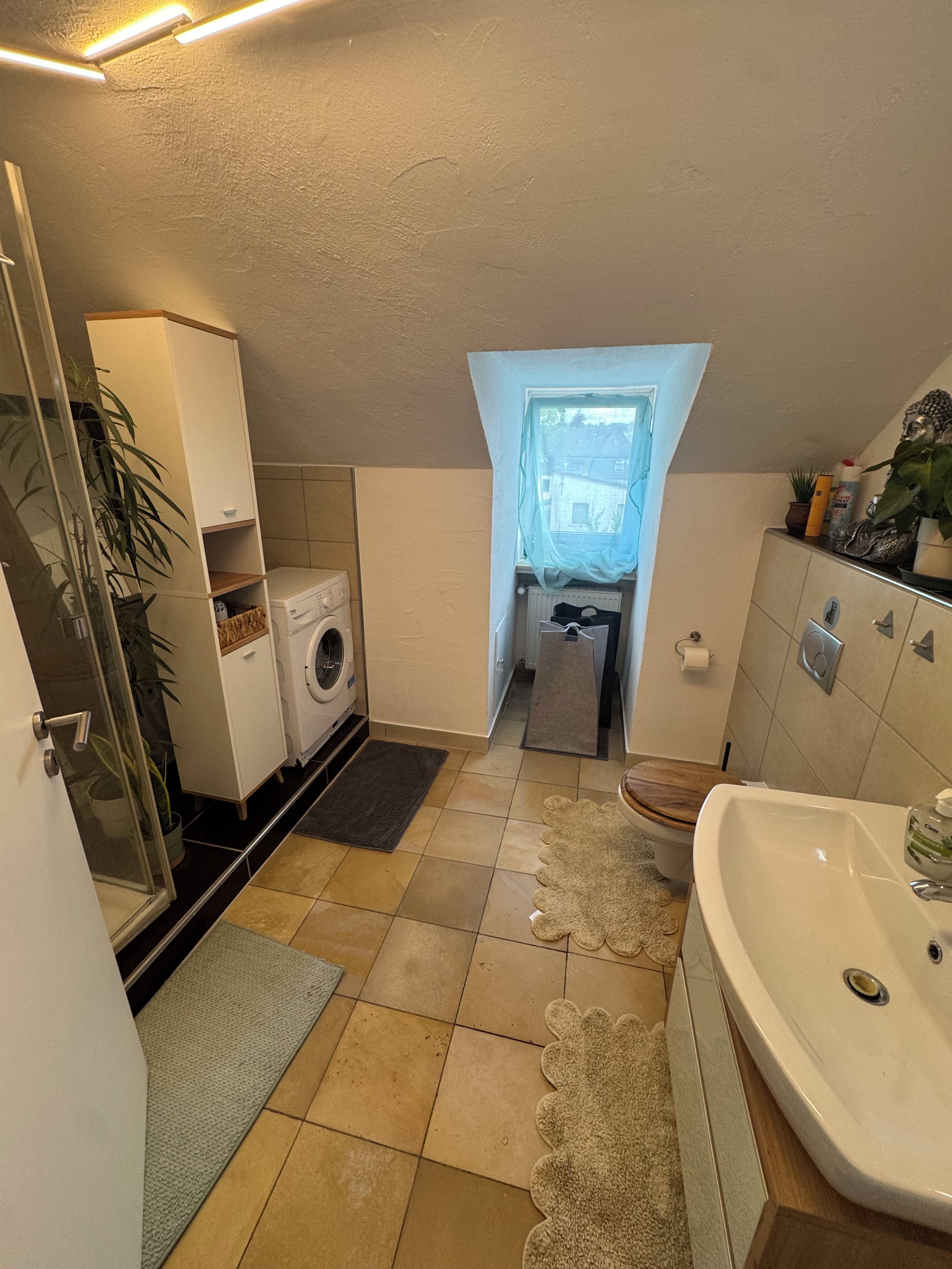 Ein kleines Badezimmer mit Waschmaschine, Toilette und Waschbecken.