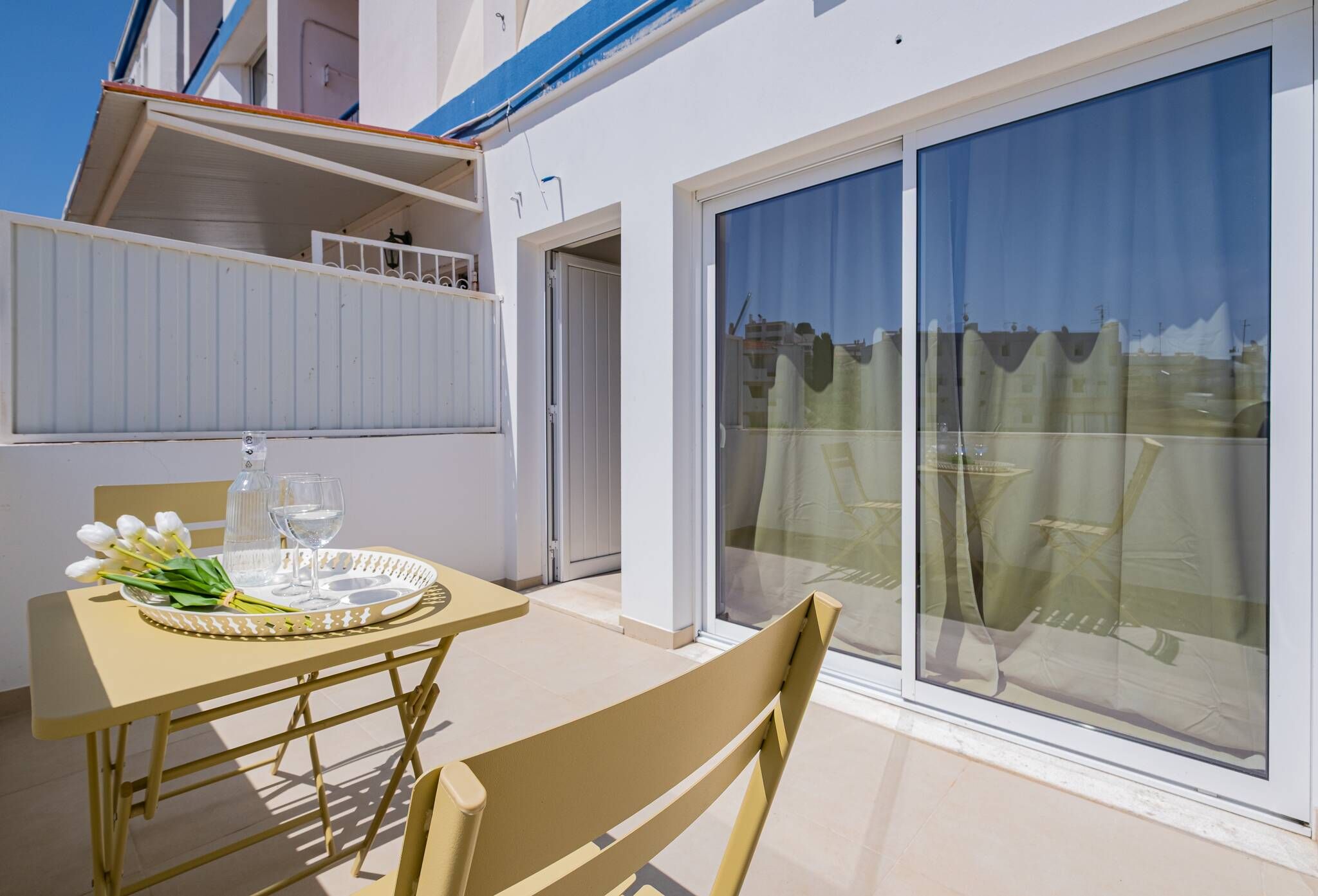 A balcony with a table set for two, a chair, and a glass of water.