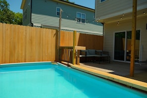A backyard with a swimming pool, wooden deck, and a covered seating area. - Pool and Games New Modern Home (Durham)