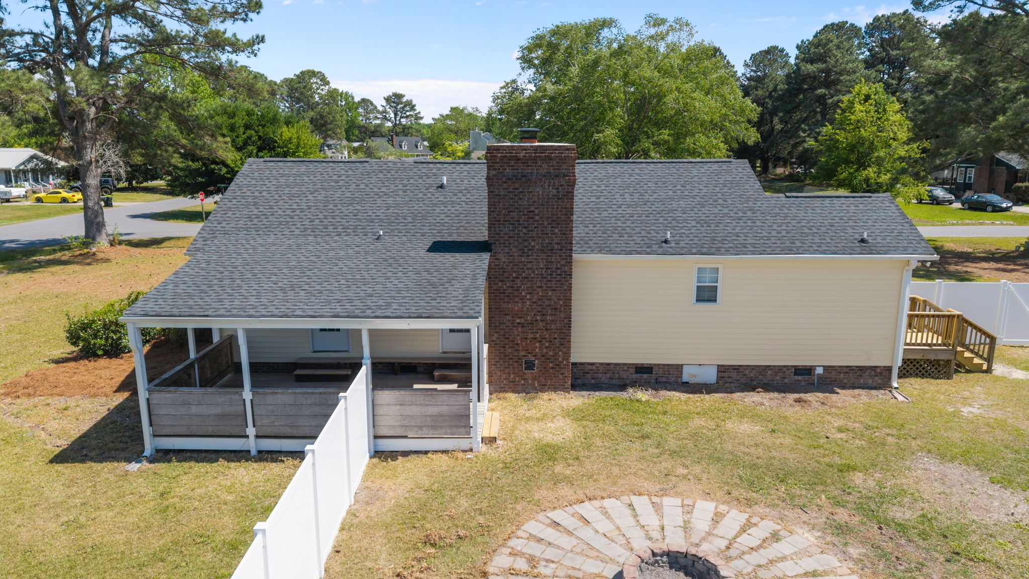 A two-story house with a covered porch and a brick chimney.